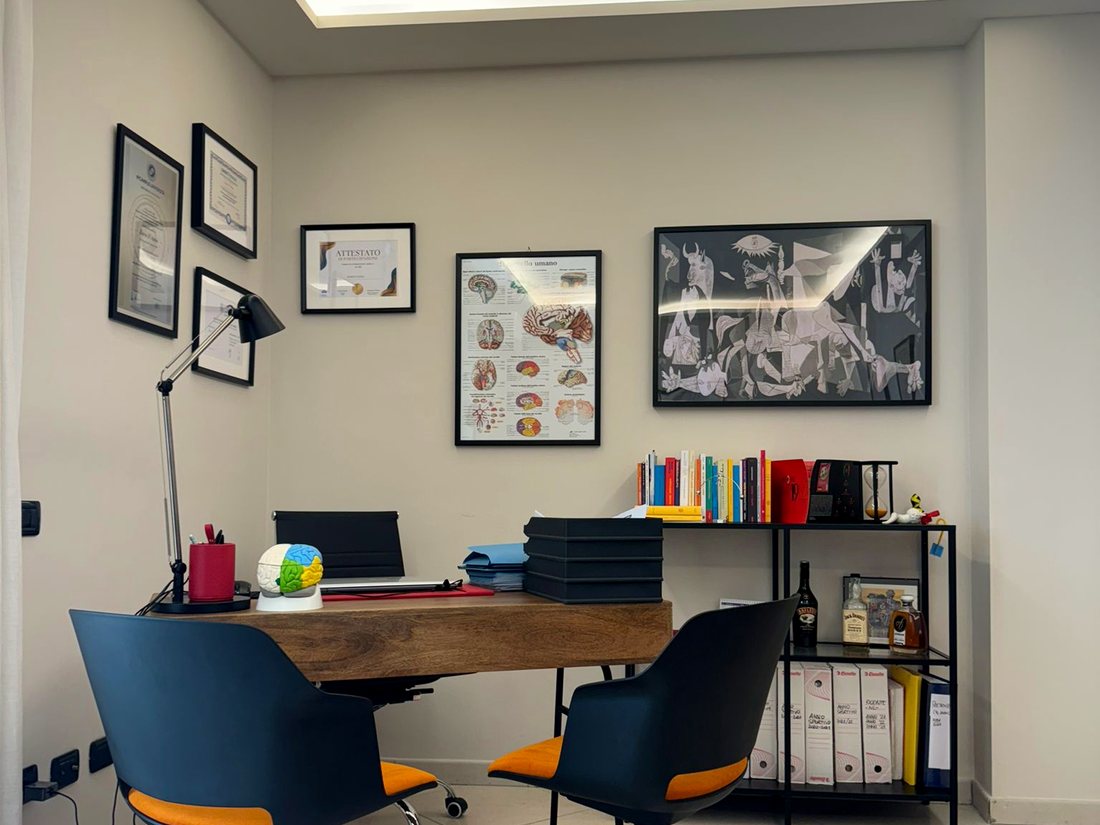 La scrivania dello studio con libreria e attestati